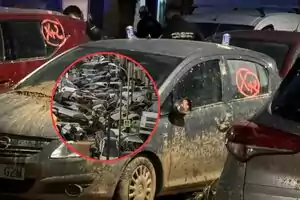 Coches cubiertos de barro con marcas rojas en las ventanas y un círculo resaltado mostrando una calle llena de vehículos apilados.