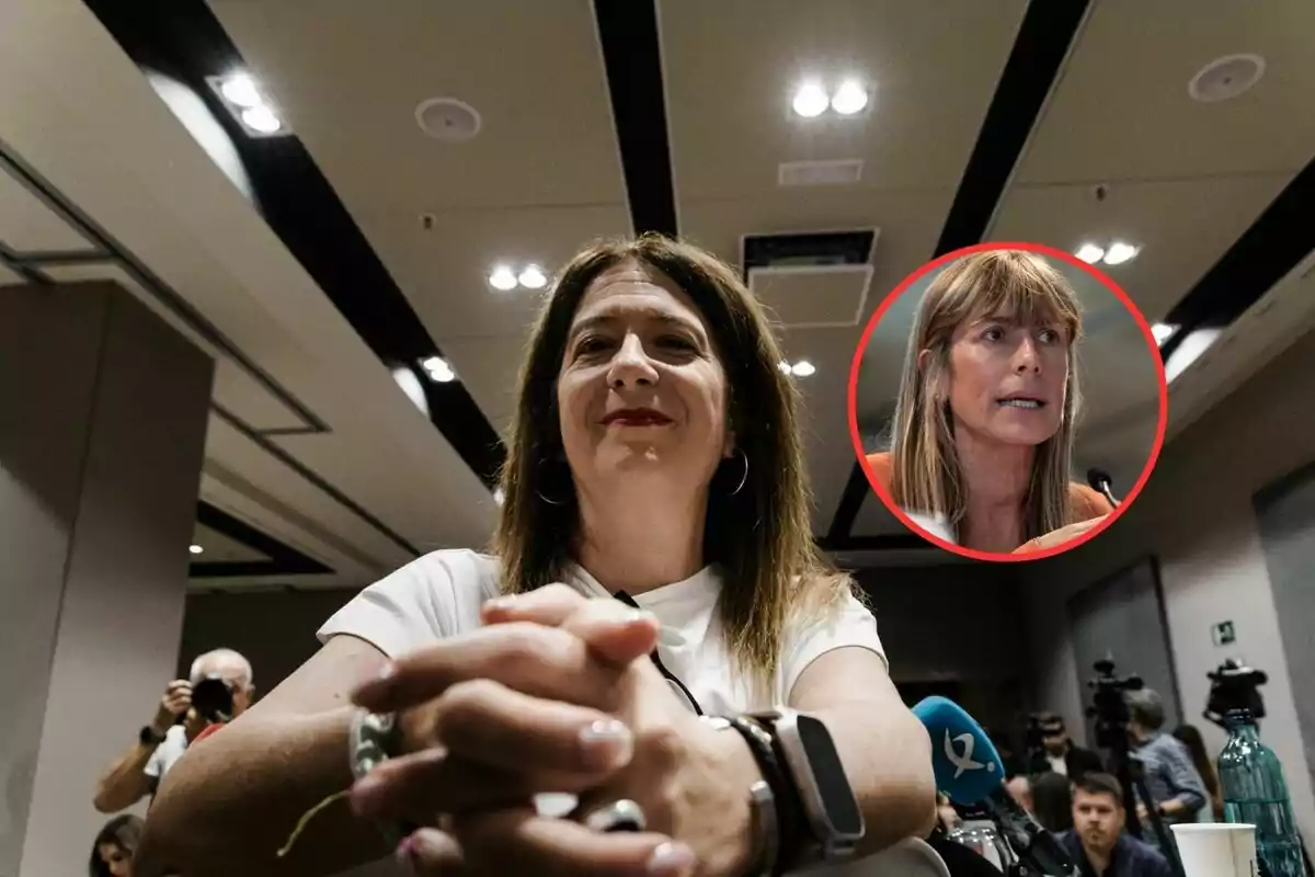 Mujer sentada en una sala de conferencias con las manos entrelazadas y una expresión seria, al fondo varias personas y cámaras, con un recuadro que muestra el rostro de otra mujer hablando