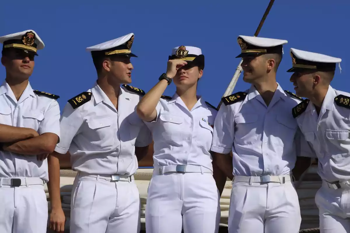 A group of naval cadets in white uniforms posing together under a blue sky. A group of naval cadets in white uniforms posing together under a blue sky.
