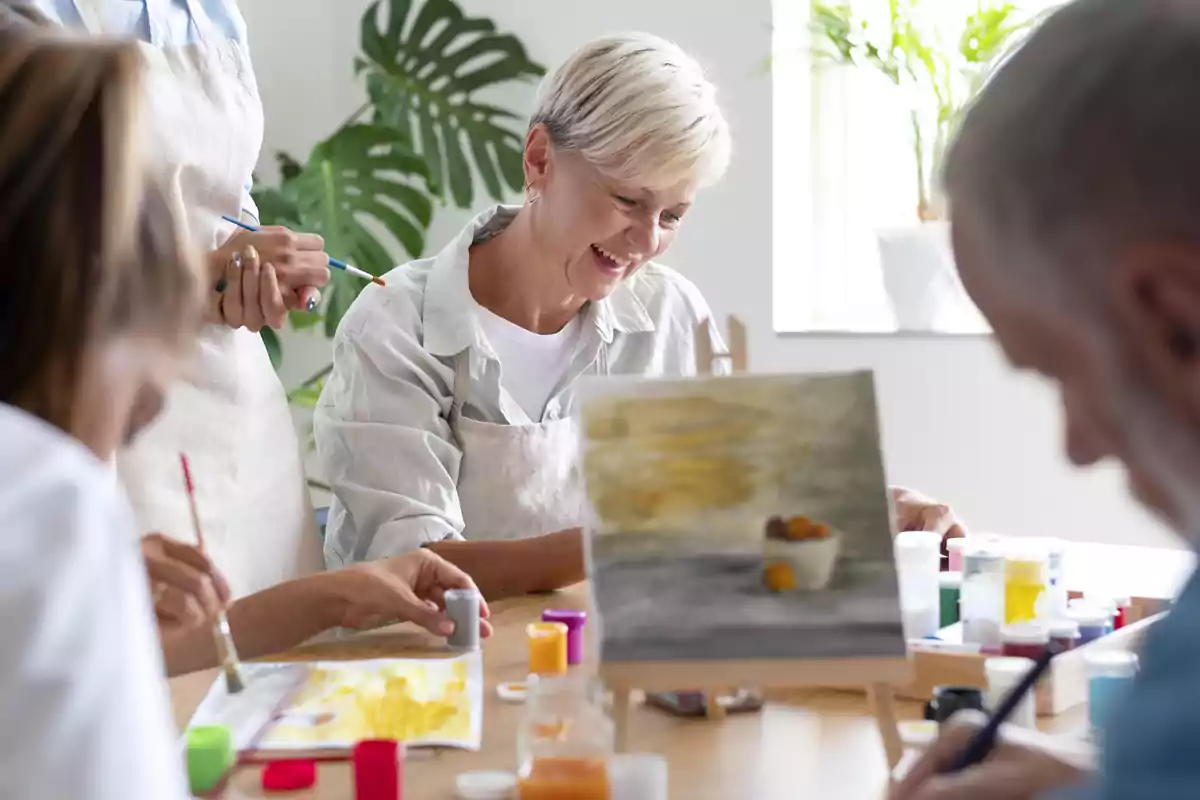 Un grupo de personas de diferentes edades participa en una clase de pintura, donde se les ve concentrados y disfrutando mientras trabajan en sus obras de arte.