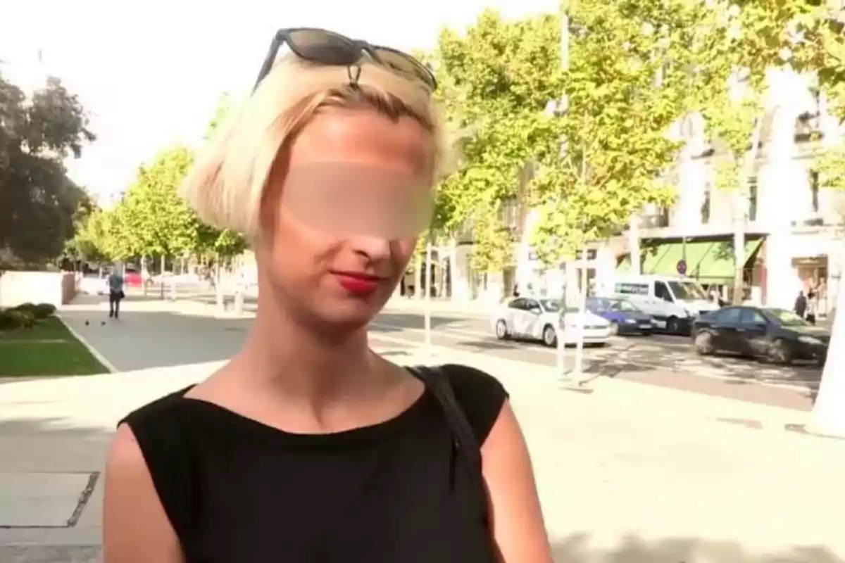 Mujer de cabello rubio corto con gafas de sol en la cabeza y labios rojos, de pie en una calle soleada con árboles y autos al fondo, con el rostro parcialmente difuminado para proteger su identidad Mujer de cabello rubio corto con gafas de sol en la cabeza y labios rojos, de pie en una calle soleada con árboles y autos al fondo, con el rostro parcialmente difuminado para proteger su identidad