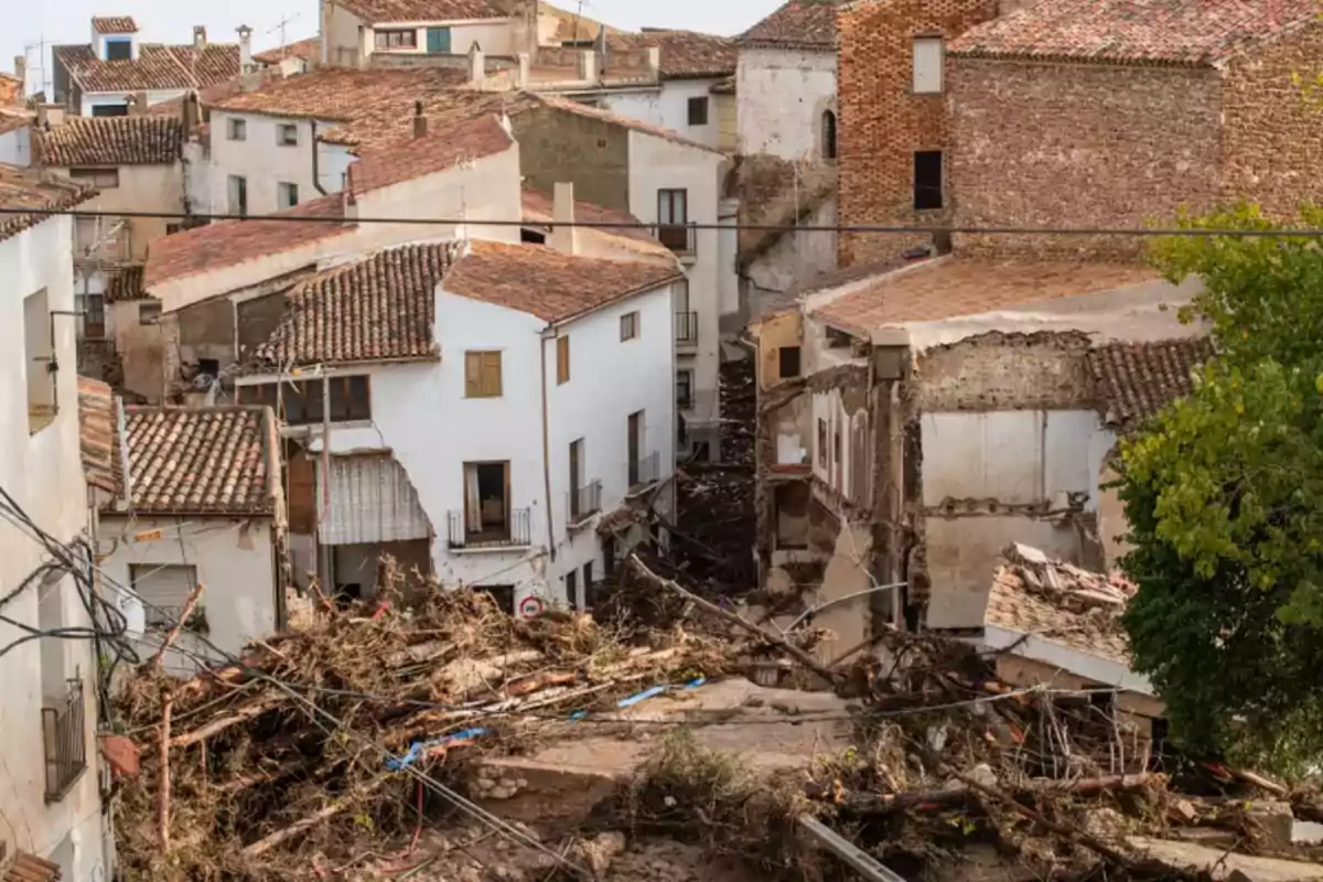 Casas dañadas por un deslizamiento de tierra en un pueblo con techos de tejas y escombros acumulados en las calles.