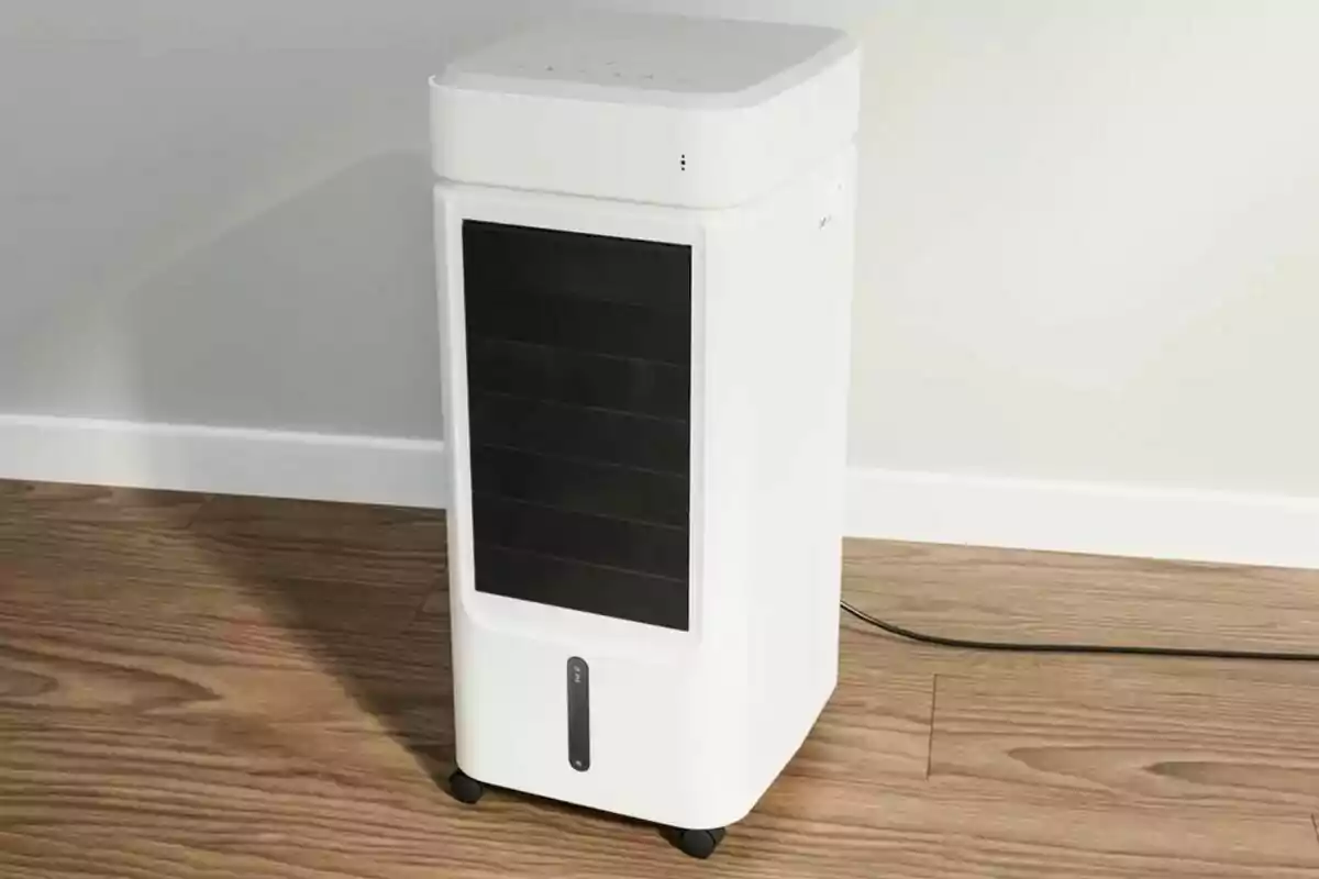 Un enfriador de aire portátil blanco sobre un suelo de madera. Un enfriador de aire portátil blanco sobre un suelo de madera.
