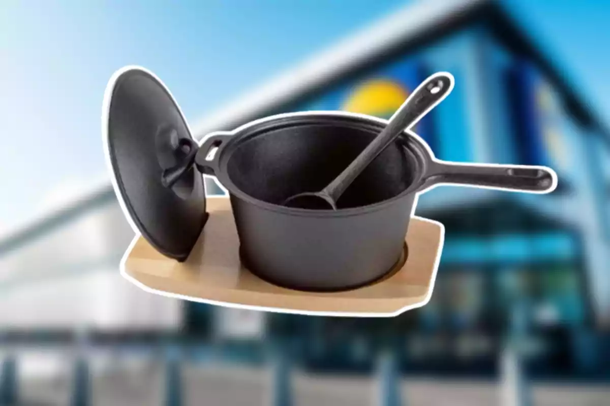 Olla de hierro fundido con tapa y cuchara sobre una base de madera con un fondo desenfocado de un edificio moderno Olla de hierro fundido con tapa y cuchara sobre una base de madera con un fondo desenfocado de un edificio moderno