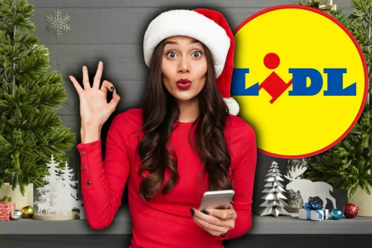Mujer con gorro navideño y suéter rojo sosteniendo un teléfono móvil, haciendo un gesto de aprobación con la mano frente a un fondo decorado con motivos navideños y el logo de Lidl.