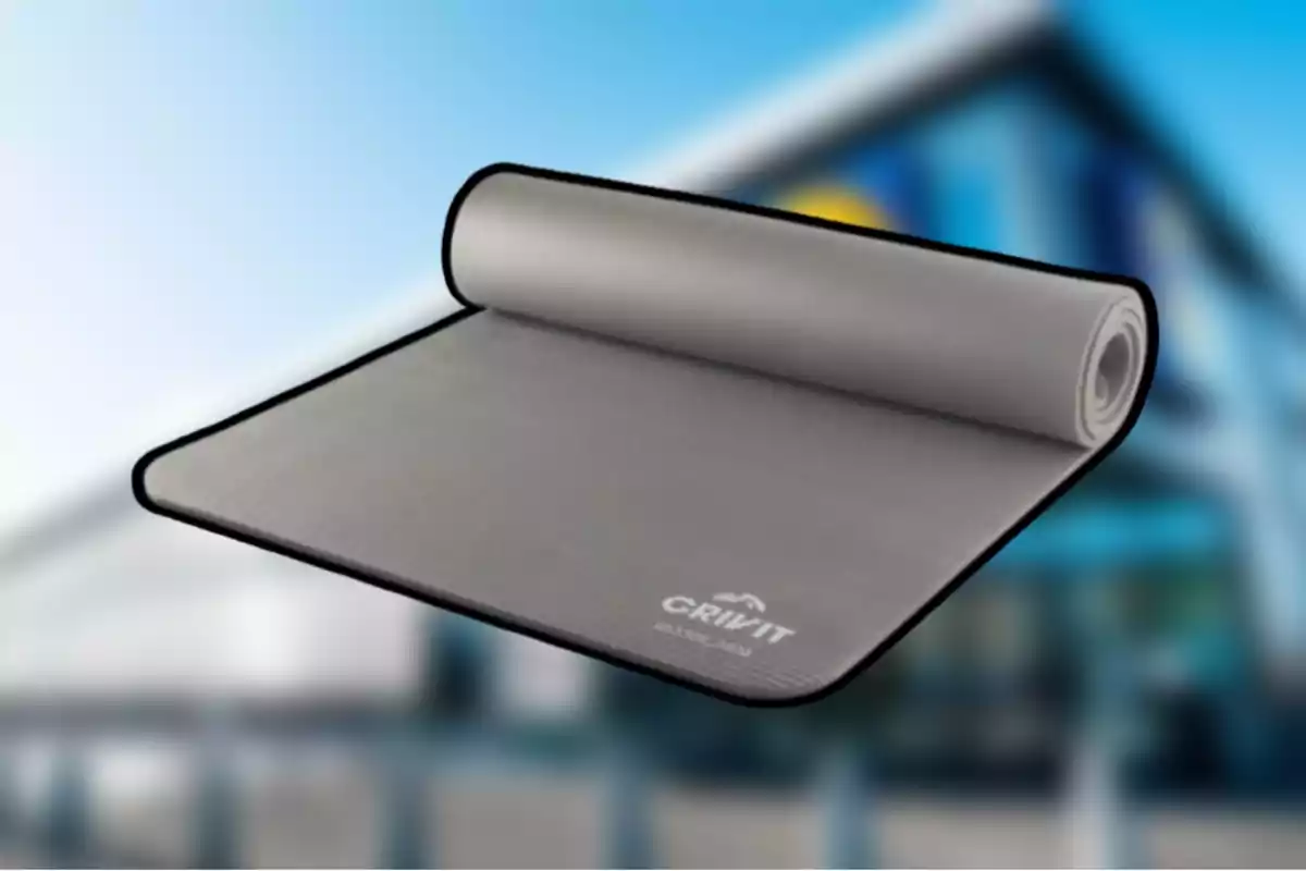 Una esterilla de yoga gris enrollada parcialmente sobre un fondo desenfocado. Una esterilla de yoga gris enrollada parcialmente sobre un fondo desenfocado.