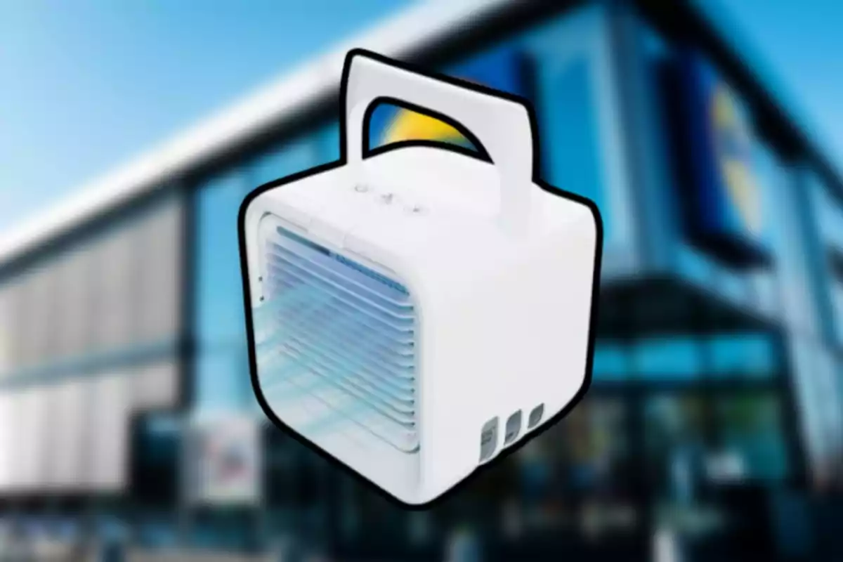 Pequeño enfriador de aire portátil blanco con asa sobre un fondo de edificio desenfocado Pequeño enfriador de aire portátil blanco con asa sobre un fondo de edificio desenfocado
