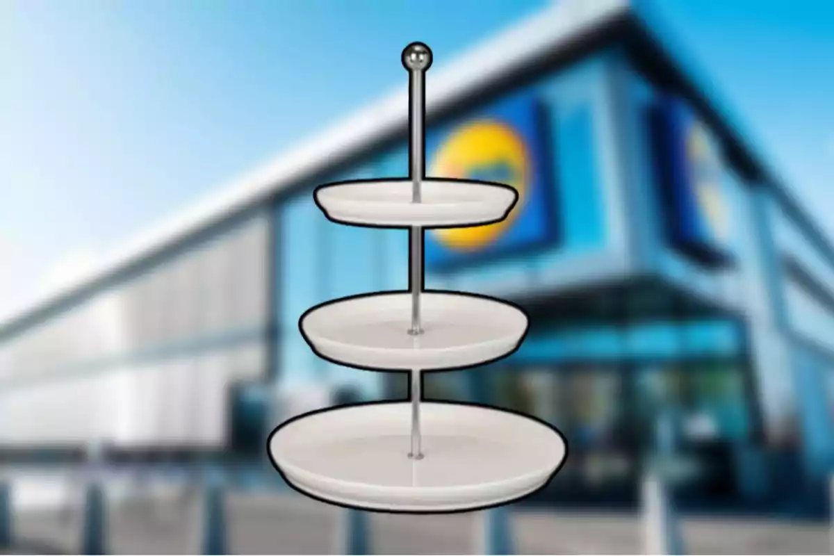 Un soporte de tres niveles con platos blancos frente a un edificio borroso. Un soporte de tres niveles con platos blancos frente a un edificio borroso.