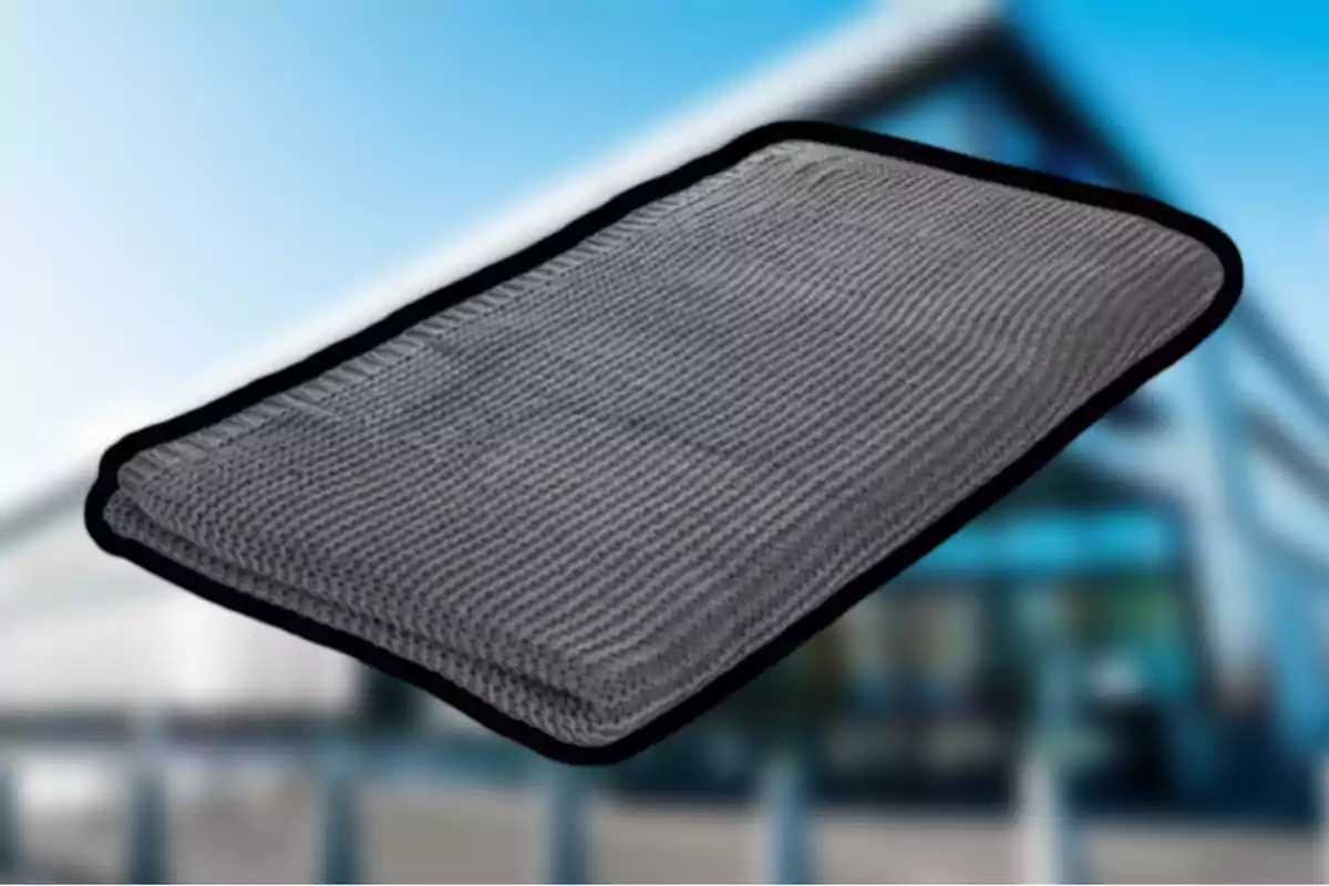 Alfombra gris rectangular con borde negro sobre un fondo desenfocado. Alfombra gris rectangular con borde negro sobre un fondo desenfocado.