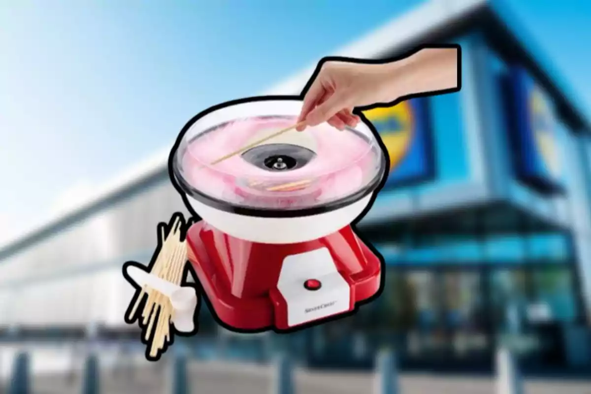 Una máquina de algodón de azúcar roja con un fondo de edificio borroso y una mano sosteniendo un palillo. Una máquina de algodón de azúcar roja con un fondo de edificio borroso y una mano sosteniendo un palillo.