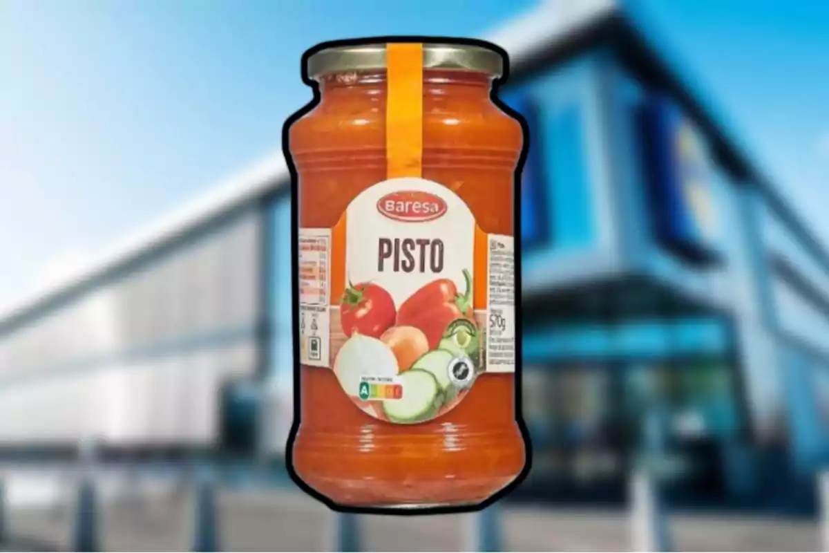 Un frasco de pisto de la marca Baresa con una etiqueta que muestra imágenes de verduras sobre un fondo desenfocado de un edificio moderno. Un frasco de pisto de la marca Baresa con una etiqueta que muestra imágenes de verduras sobre un fondo desenfocado de un edificio moderno.