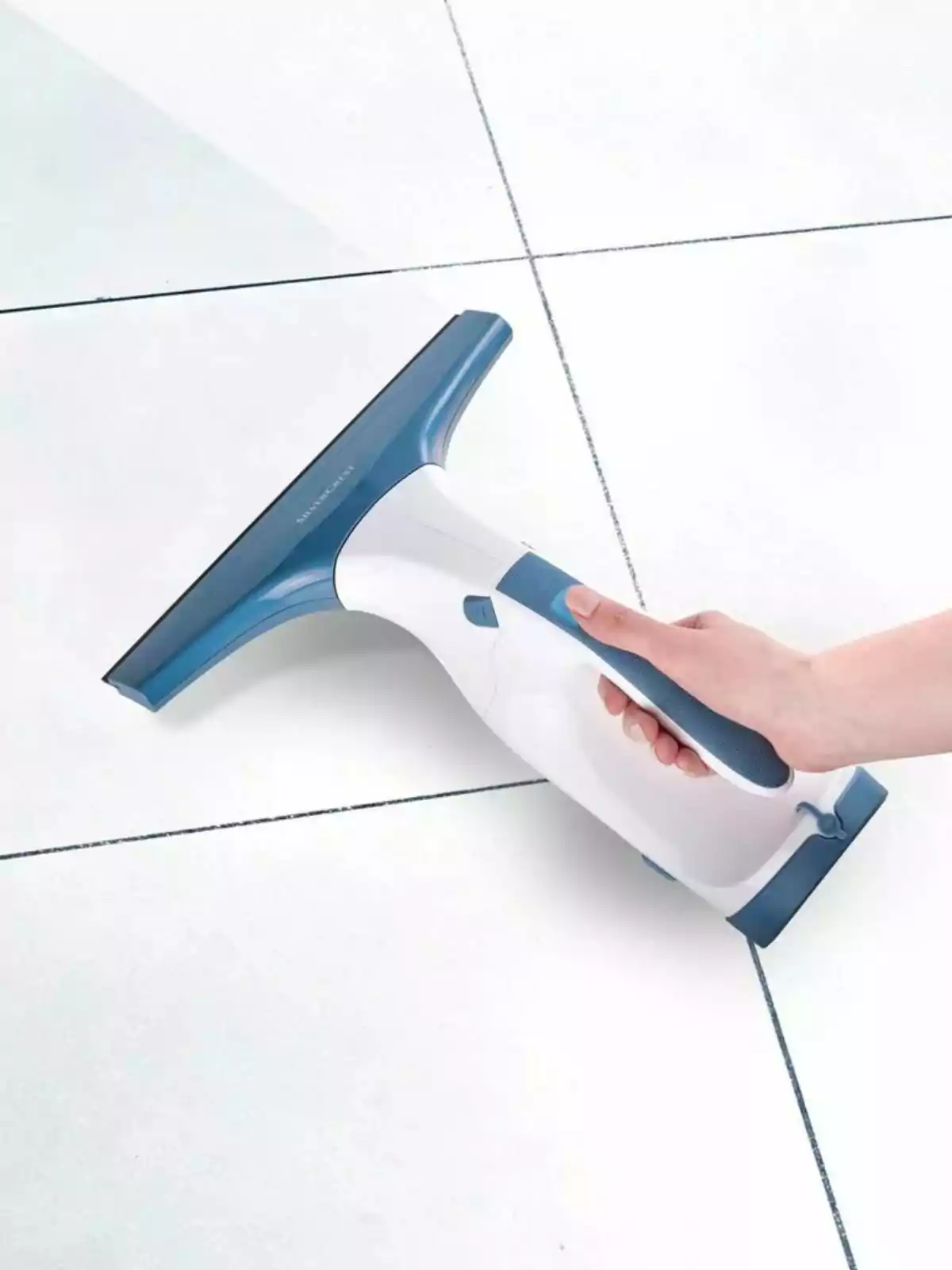 Una mano sosteniendo un limpiador de ventanas de Lidl sobre una superficie de azulejos blancos. Una mano sosteniendo un limpiador de ventanas de Lidl sobre una superficie de azulejos blancos.