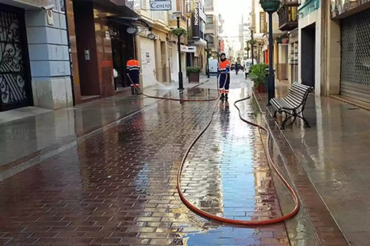 Trabajos de limpieza con mangueras lavan una calle peatonal de Castellón