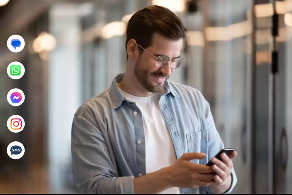 Hombre sonriendo mientras usa su teléfono móvil con iconos de aplicaciones de mensajería a la izquierda.