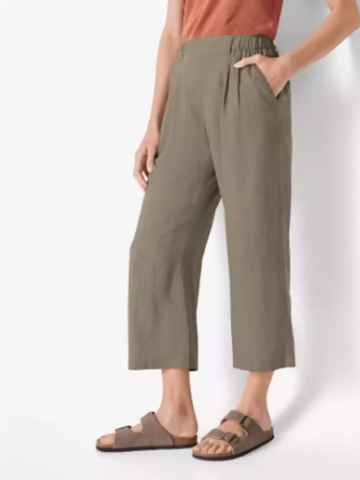 Persona vistiendo pantalones holgados de color verde oliva, camiseta sin mangas color terracota y sandalias marrones Persona vistiendo pantalones holgados de color verde oliva, camiseta sin mangas color terracota y sandalias marrones