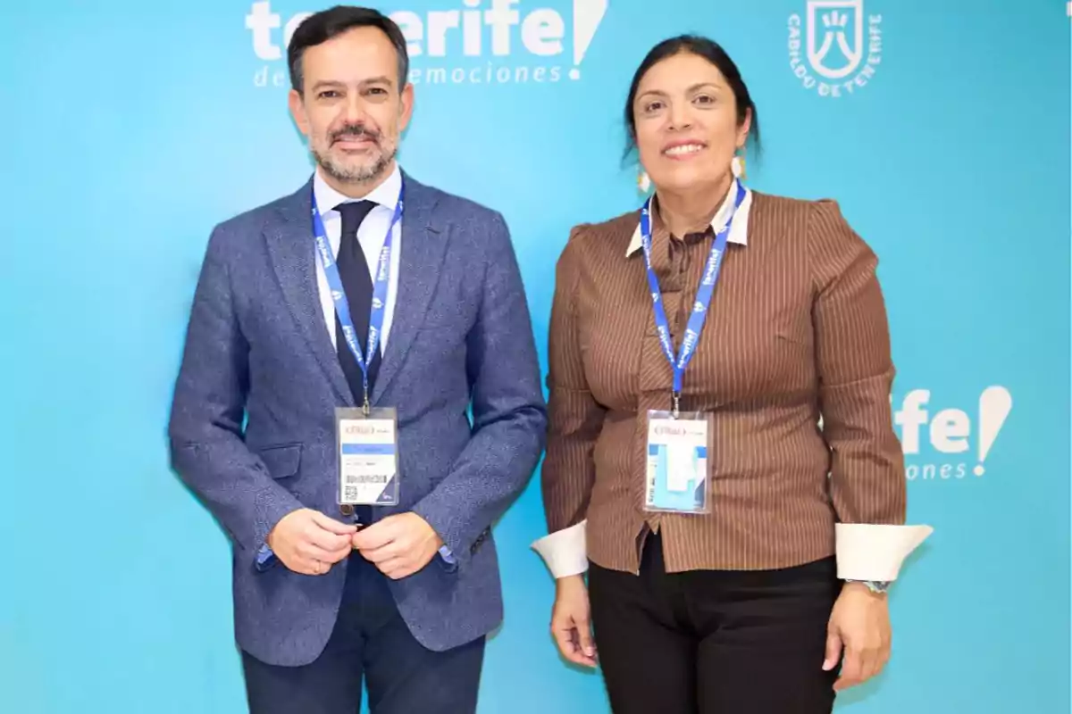 Dos personas posando frente a un fondo azul con el logotipo de Tenerife.