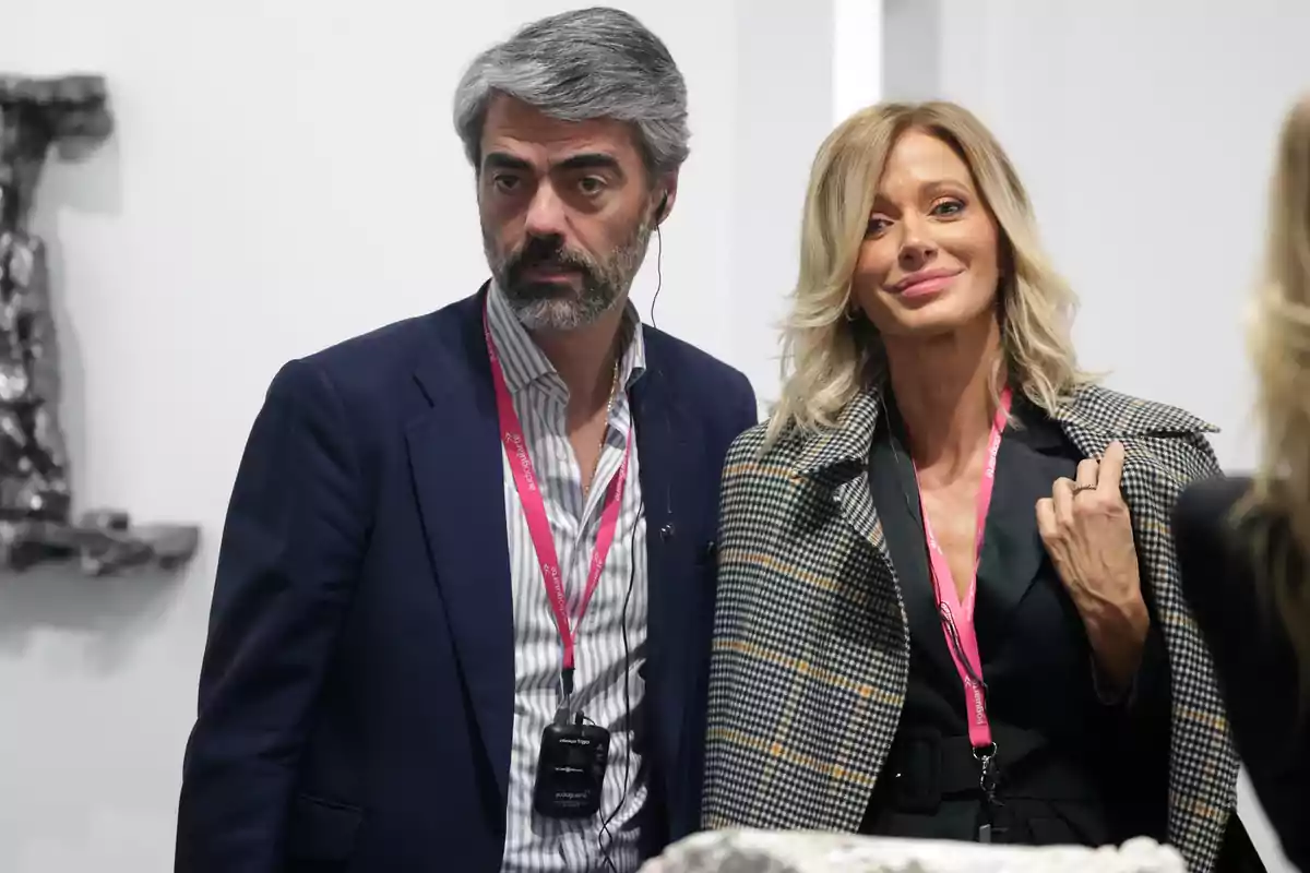 Luis Enríquez Nistal y Susanna Griso con gafetes rosas posan juntas en un evento, una de ellas lleva un abrigo de cuadros y la otra viste un saco azul marino. Luis Enríquez Nistal y Susanna Griso con gafetes rosas posan juntas en un evento, una de ellas lleva un abrigo de cuadros y la otra viste un saco azul marino.