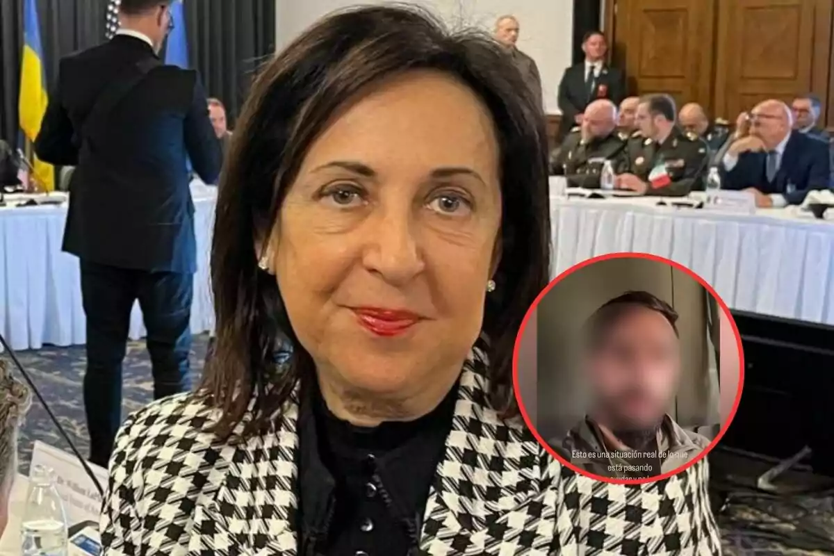 Una mujer con cabello oscuro y labios rojos está en una sala de conferencias con varias personas sentadas al fondo.