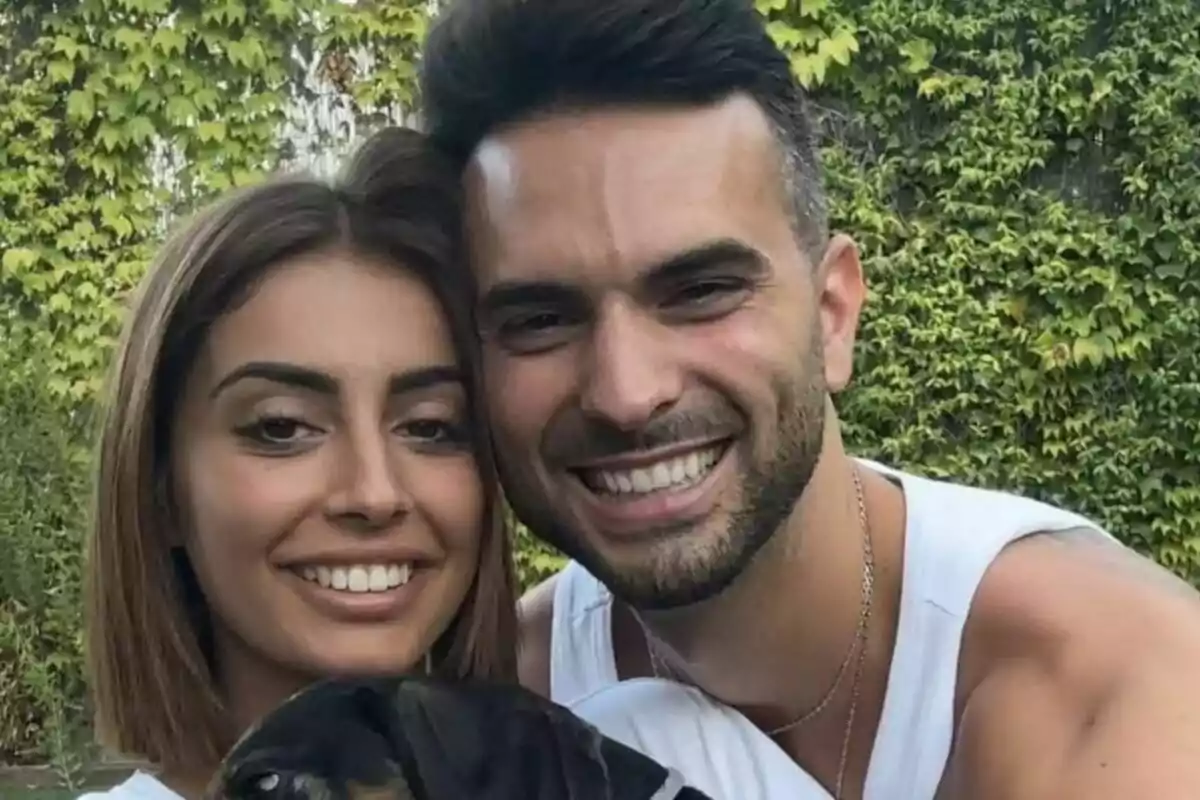 Captura de Marieta Díaz y Suso Álvarez sonriente posando con un perro frente a un fondo de vegetación.