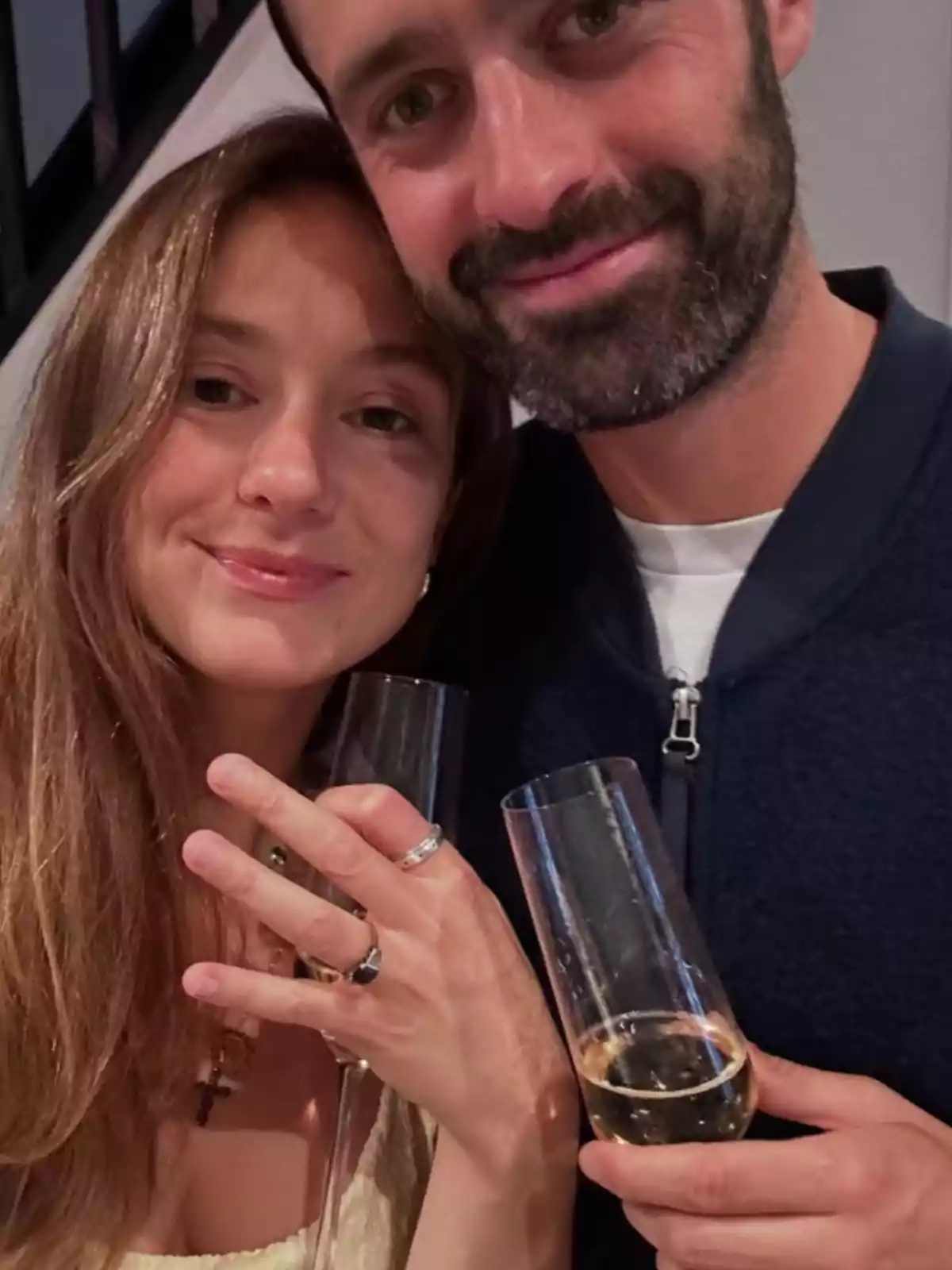 Smiling couple toasting with champagne glasses while the woman shows a ring on her hand Smiling couple toasting with champagne glasses while the woman shows a ring on her hand