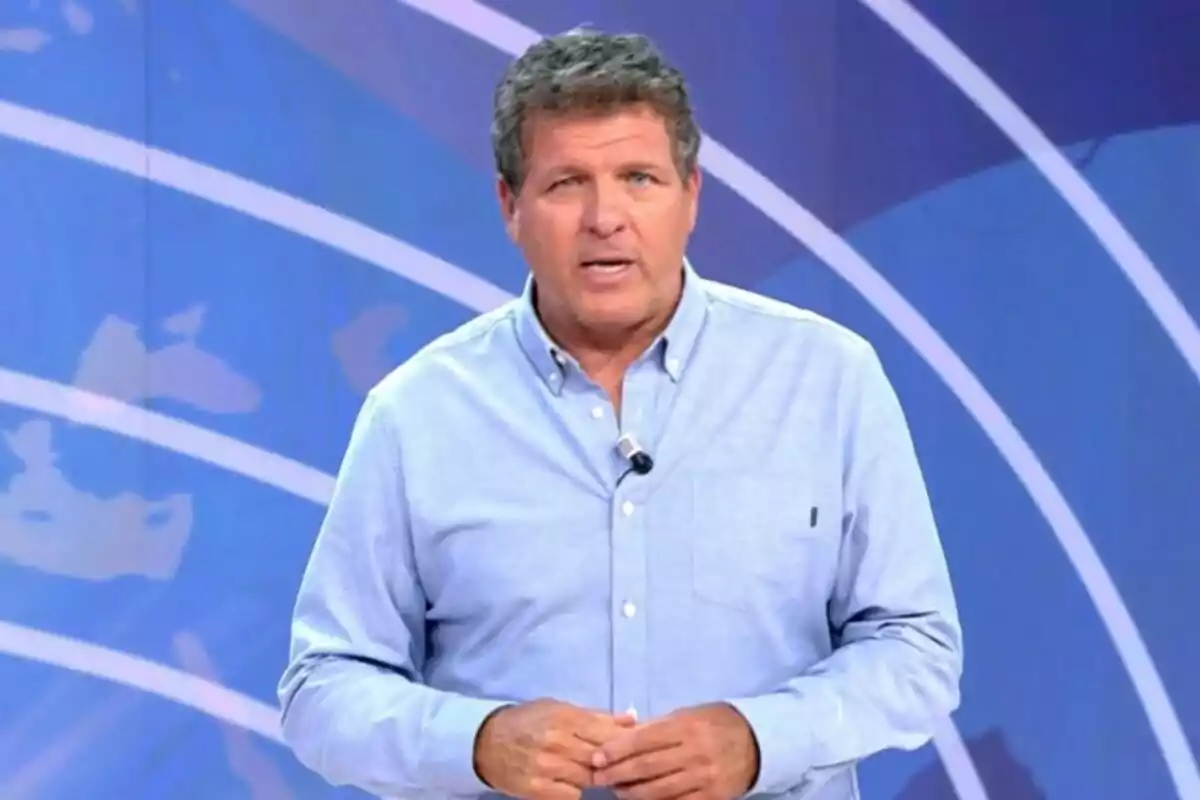 Mario Picazo con camisa azul claro hablando frente a un fondo azul con líneas curvas blancas. Mario Picazo con camisa azul claro hablando frente a un fondo azul con líneas curvas blancas.