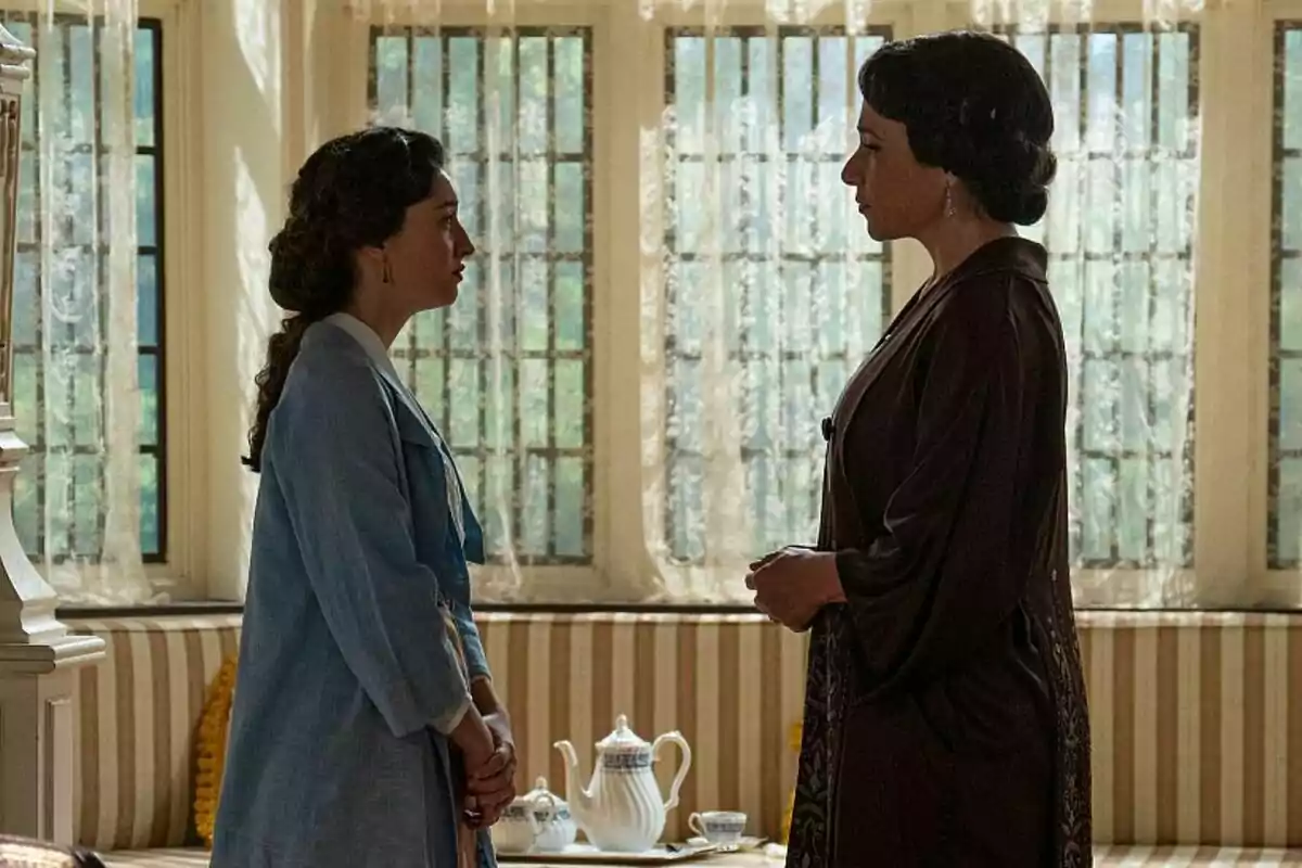 Marta Costa and Isabel Serrano standing face to face in a room lit by natural light coming through the windows behind them in La Promesa.