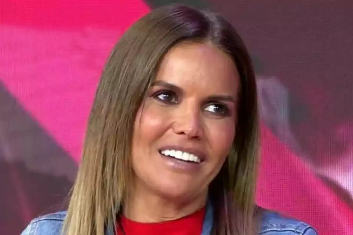Marta López sonriendo con fondo rojo y chaqueta de mezclilla en Tardear. Marta López sonriendo con fondo rojo y chaqueta de mezclilla en Tardear.
