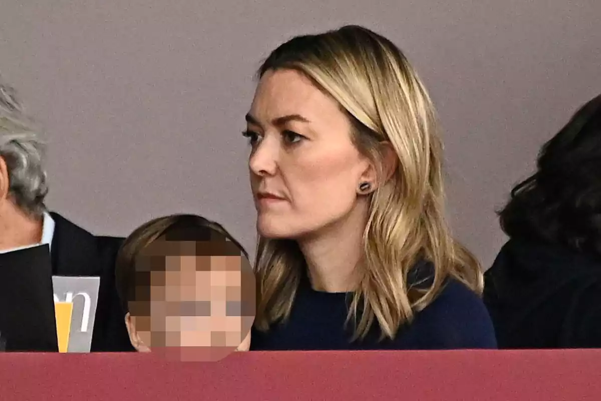 Marta Ortega con expresión seria está sentada junto a un niño cuyo rostro está pixelado. Marta Ortega con expresión seria está sentada junto a un niño cuyo rostro está pixelado.