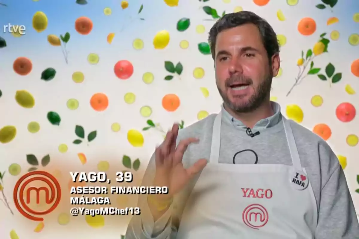 Yago usando un delantal blanco con el nombre Yago y un pin que dice I love Rafa, hablando frente a un fondo decorado con frutas y hojas, en una entrevista de un programa de cocina. Captura de 'MasterChef' Yago usando un delantal blanco con el nombre Yago y un pin que dice I love Rafa, hablando frente a un fondo decorado con frutas y hojas, en una entrevista de un programa de cocina. Captura de 'MasterChef'