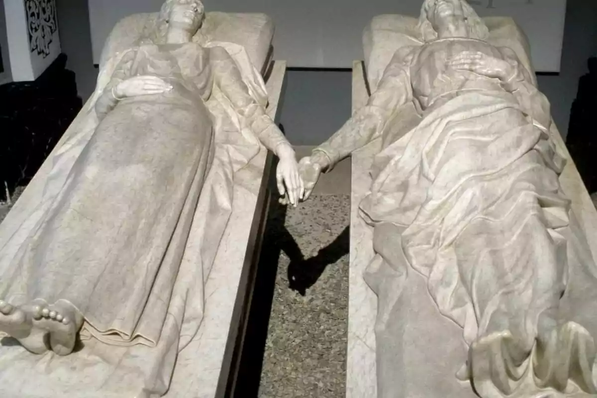 Esculturas de dos figuras yacentes tomadas de la mano.