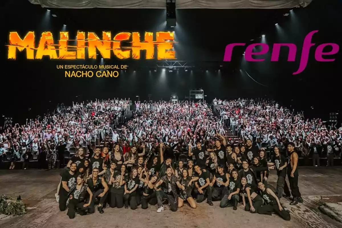 Elenco del musical "Malinche" de Nacho Cano posando frente a una multitud de espectadores, con los logotipos de "Malinche" y "Renfe" en el fondo.