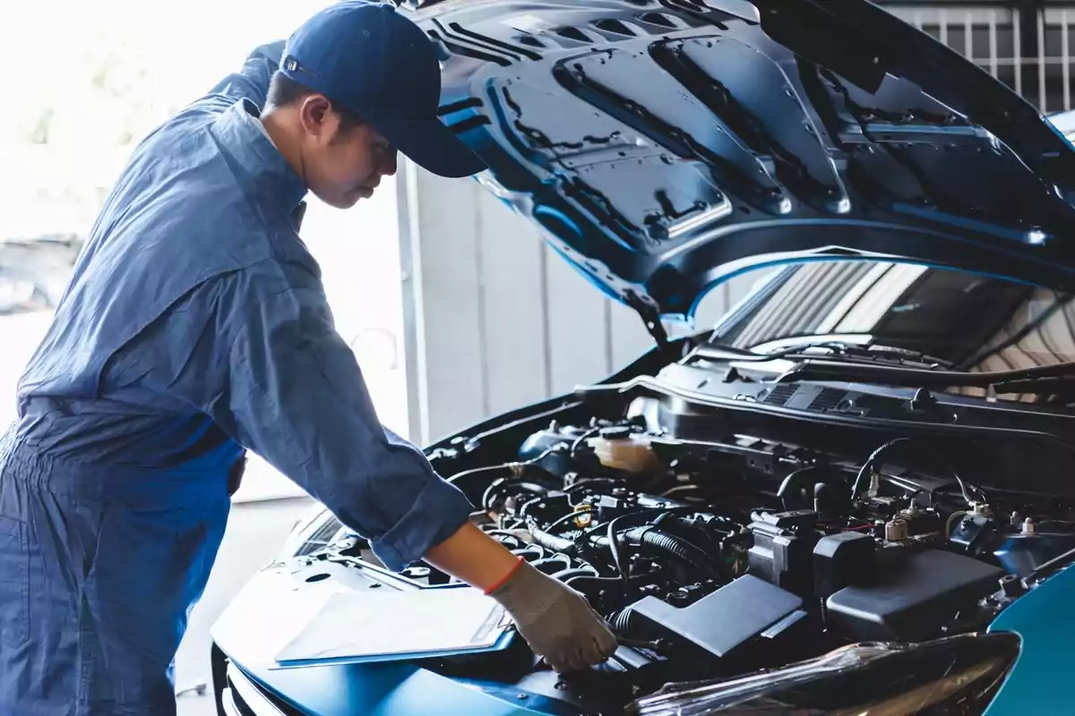 Mecánico trabajando en el motor de un automóvil con el capó levantado.