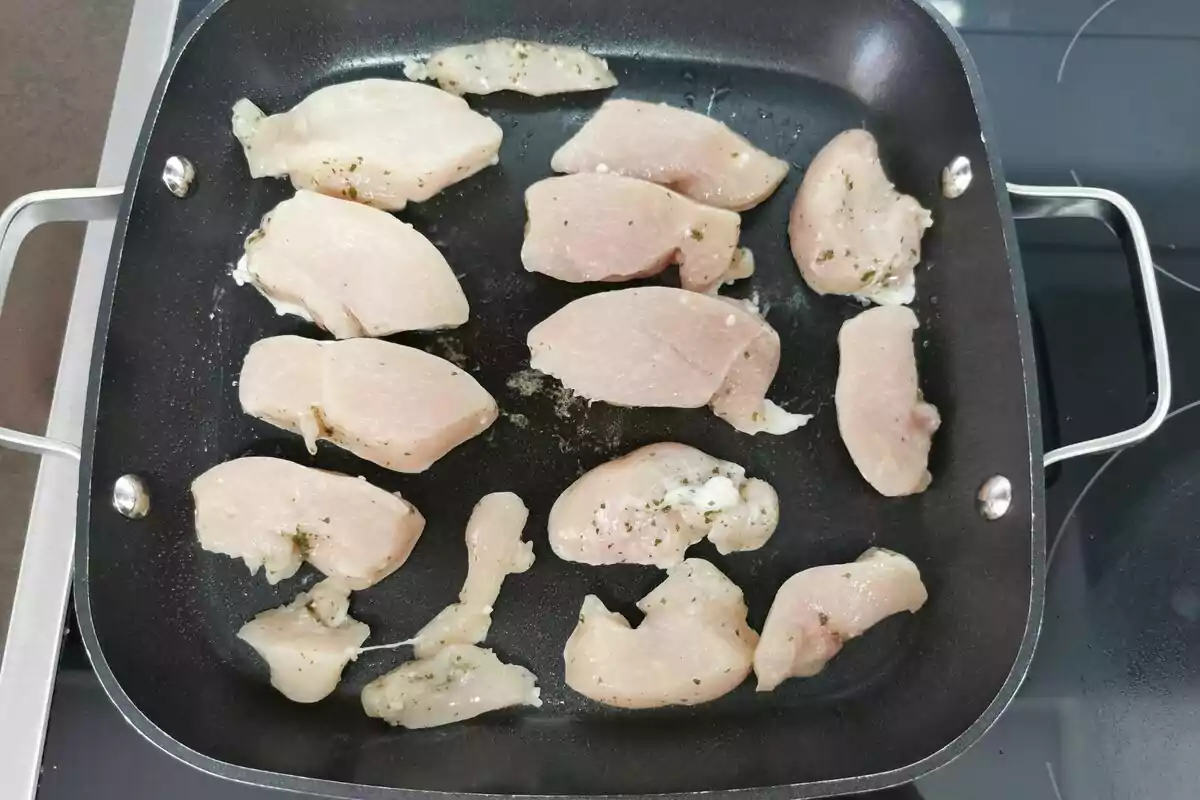 Trozos de pollo crudo sazonados en una sartén antiadherente. Trozos de pollo crudo sazonados en una sartén antiadherente.