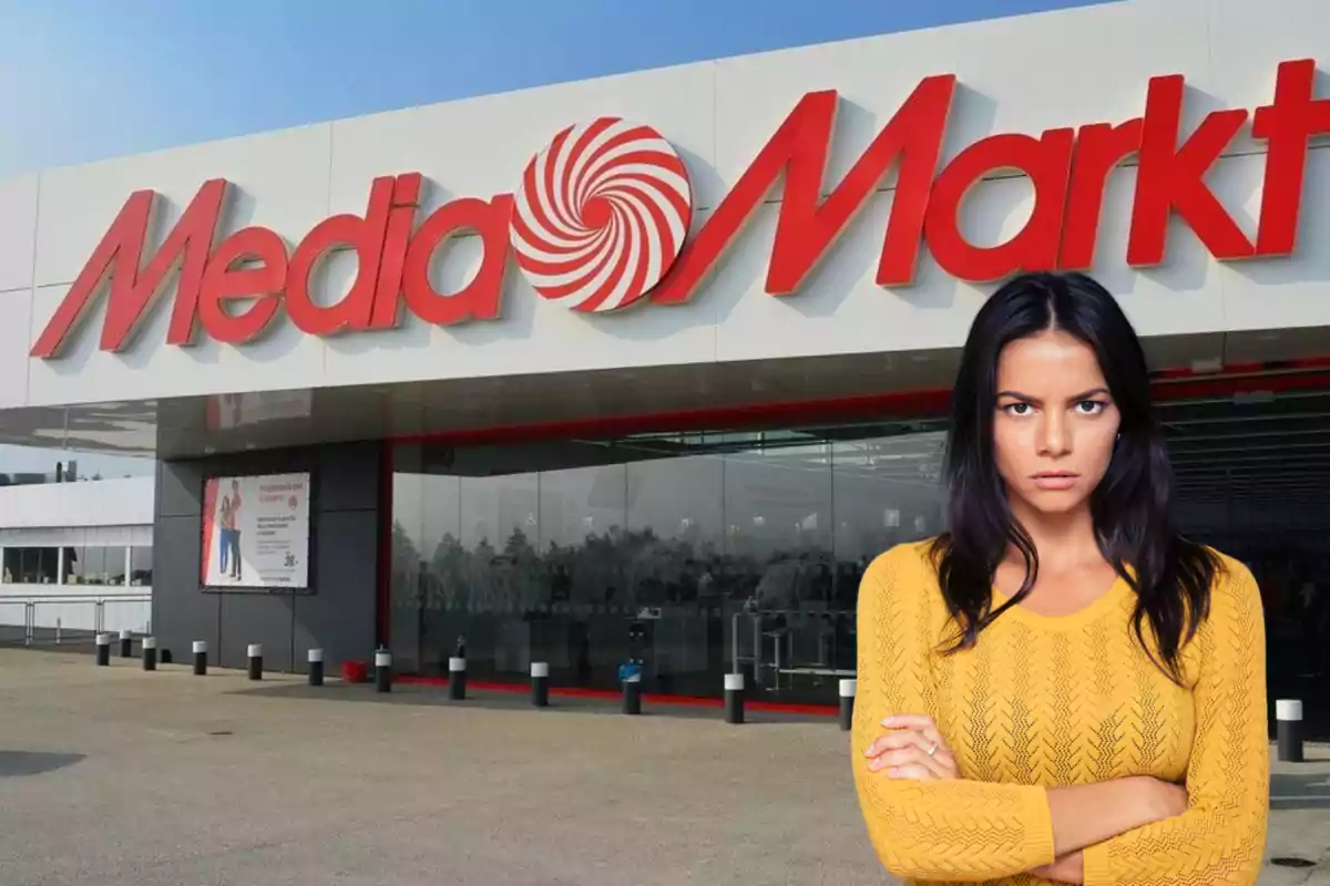 Una mujer con suéter amarillo está de pie frente a una tienda MediaMarkt con expresión seria.