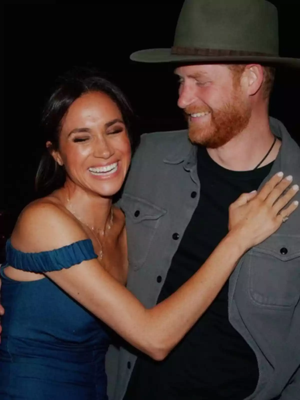 A smiling couple embraces, the woman is wearing a blue dress and the man a green hat. A smiling couple embraces, the woman is wearing a blue dress and the man a green hat.