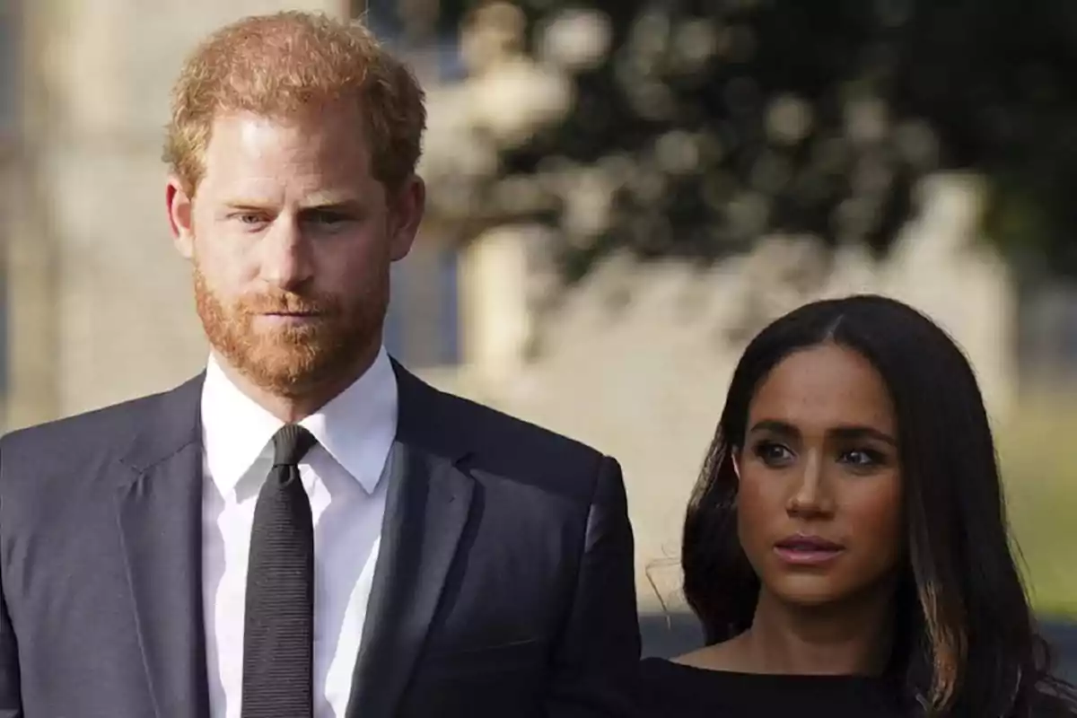 Una pareja vestida formalmente, el hombre con traje y corbata y la mujer con un vestido negro, caminando juntos al aire libre.