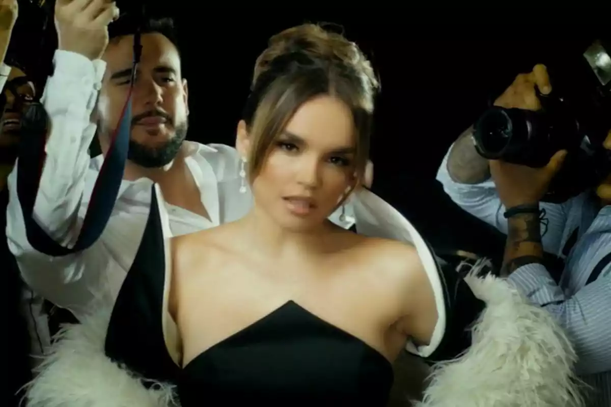 Melody con un elegante vestido negro y un abrigo de plumas blancas es fotografiada por varios fotógrafos en un ambiente de alfombra roja en el videoclip de Esa Diva. Melody con un elegante vestido negro y un abrigo de plumas blancas es fotografiada por varios fotógrafos en un ambiente de alfombra roja en el videoclip de Esa Diva.