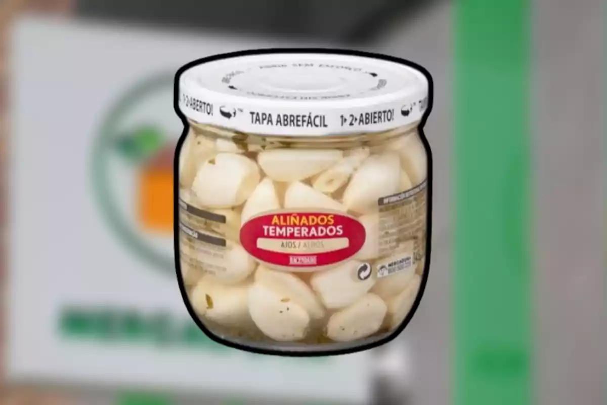 Frasco de ajos pelados en conserva con etiqueta roja y tapa blanca Frasco de ajos pelados en conserva con etiqueta roja y tapa blanca