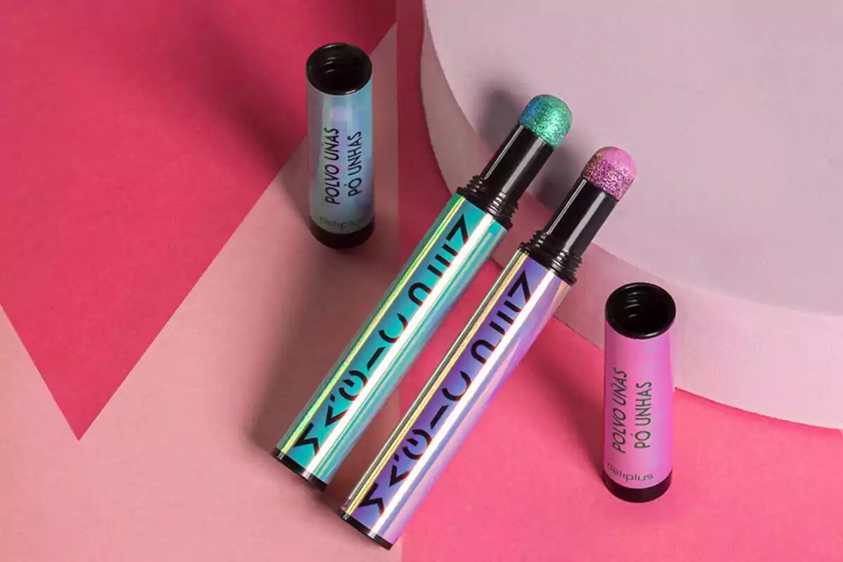Dos tubos de polvo para uñas con aplicadores de esponja en colores brillantes sobre un fondo rosa. Dos tubos de polvo para uñas con aplicadores de esponja en colores brillantes sobre un fondo rosa.