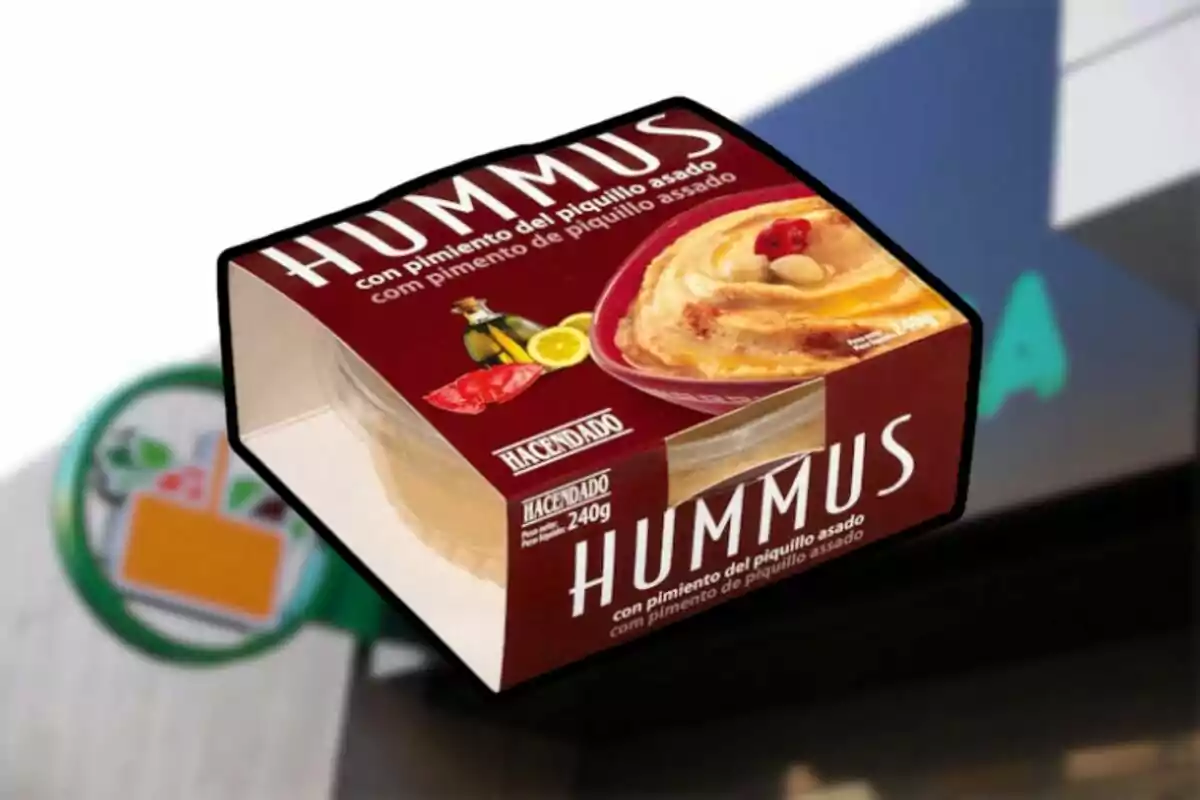 Envase de hummus con pimiento del piquillo asado de la marca Hacendado frente a un supermercado. Envase de hummus con pimiento del piquillo asado de la marca Hacendado frente a un supermercado.