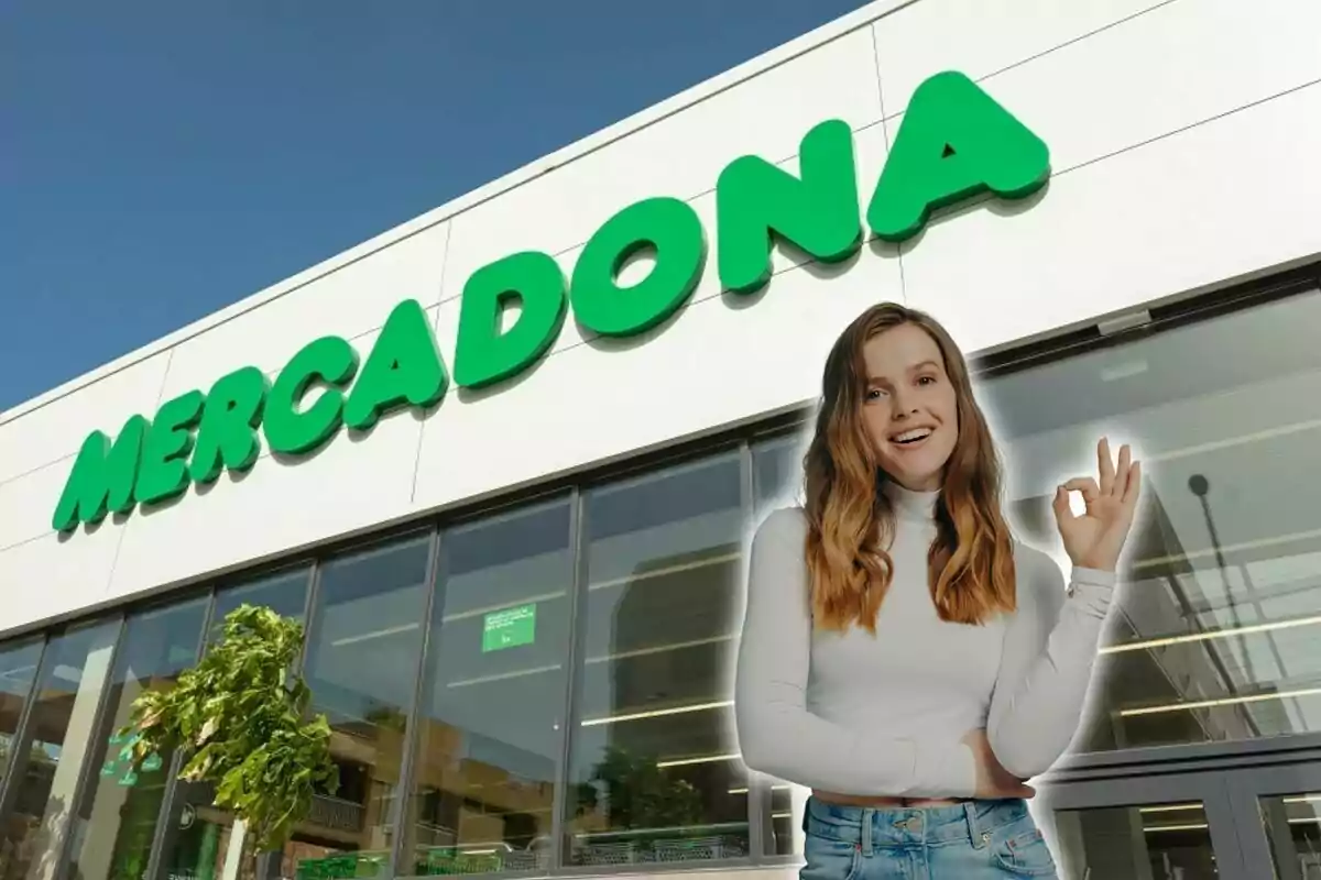 Una mujer sonriente haciendo un gesto de "ok" frente a una tienda de Mercadona.