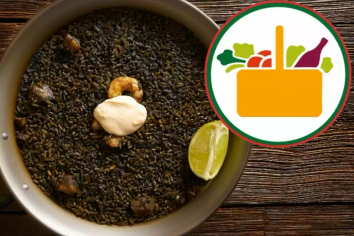 Plato de arroz negro con un camarón, una rodaja de limón y una cucharada de mayonesa en el centro, junto a un logotipo de una cesta de alimentos.