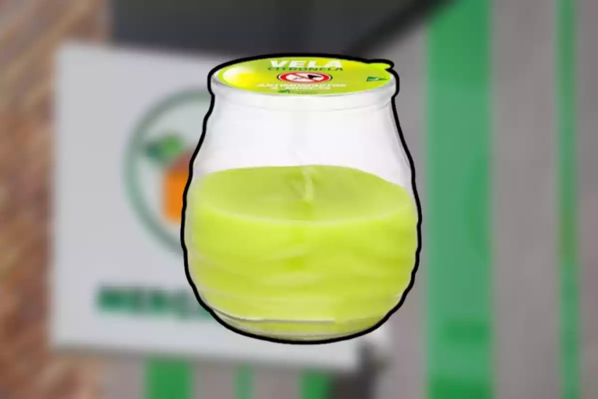 Vela amarilla en frasco de vidrio con tapa verde desenfocada al fondo Vela amarilla en frasco de vidrio con tapa verde desenfocada al fondo