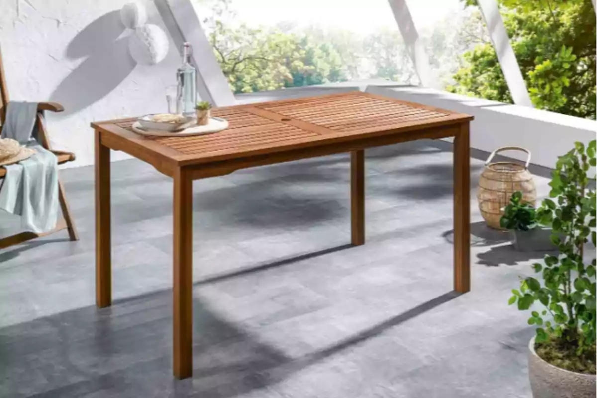 Mesa de madera en una terraza con sillas y plantas alrededor. Mesa de madera en una terraza con sillas y plantas alrededor.