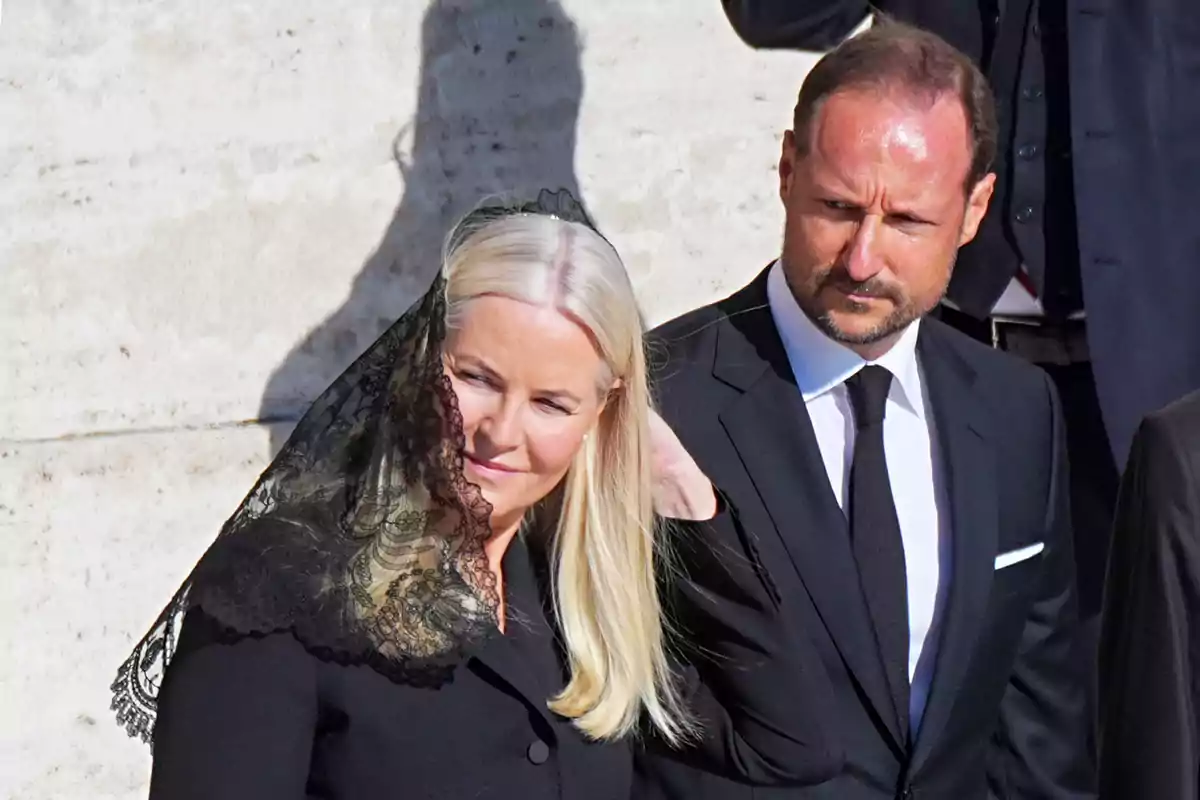 Mette-Marit con velo negro y el príncipe Haakon con traje oscuro están juntos en un evento formal.
