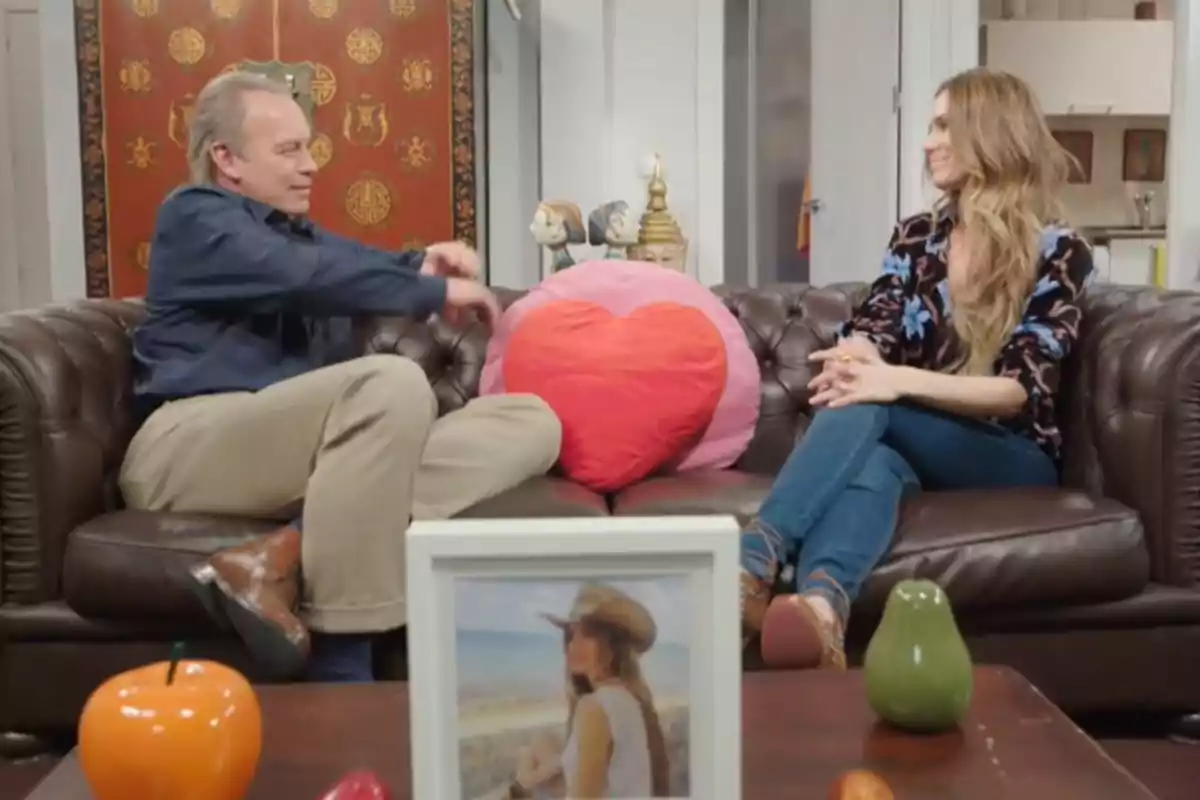 Bertín Osborne y Vanesa Romero sentadas en un sofá de cuero marrón con un cojín en forma de corazón entre ellas, en una sala decorada con objetos y una foto enmarcada sobre la mesa. Captura de 'Mi casa es la tuya' Bertín Osborne y Vanesa Romero sentadas en un sofá de cuero marrón con un cojín en forma de corazón entre ellas, en una sala decorada con objetos y una foto enmarcada sobre la mesa. Captura de 'Mi casa es la tuya'