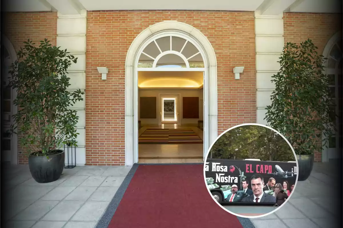 Entrada de un edificio con una alfombra roja y plantas a los lados, con un recuadro que muestra un autobús decorado con imágenes y texto.