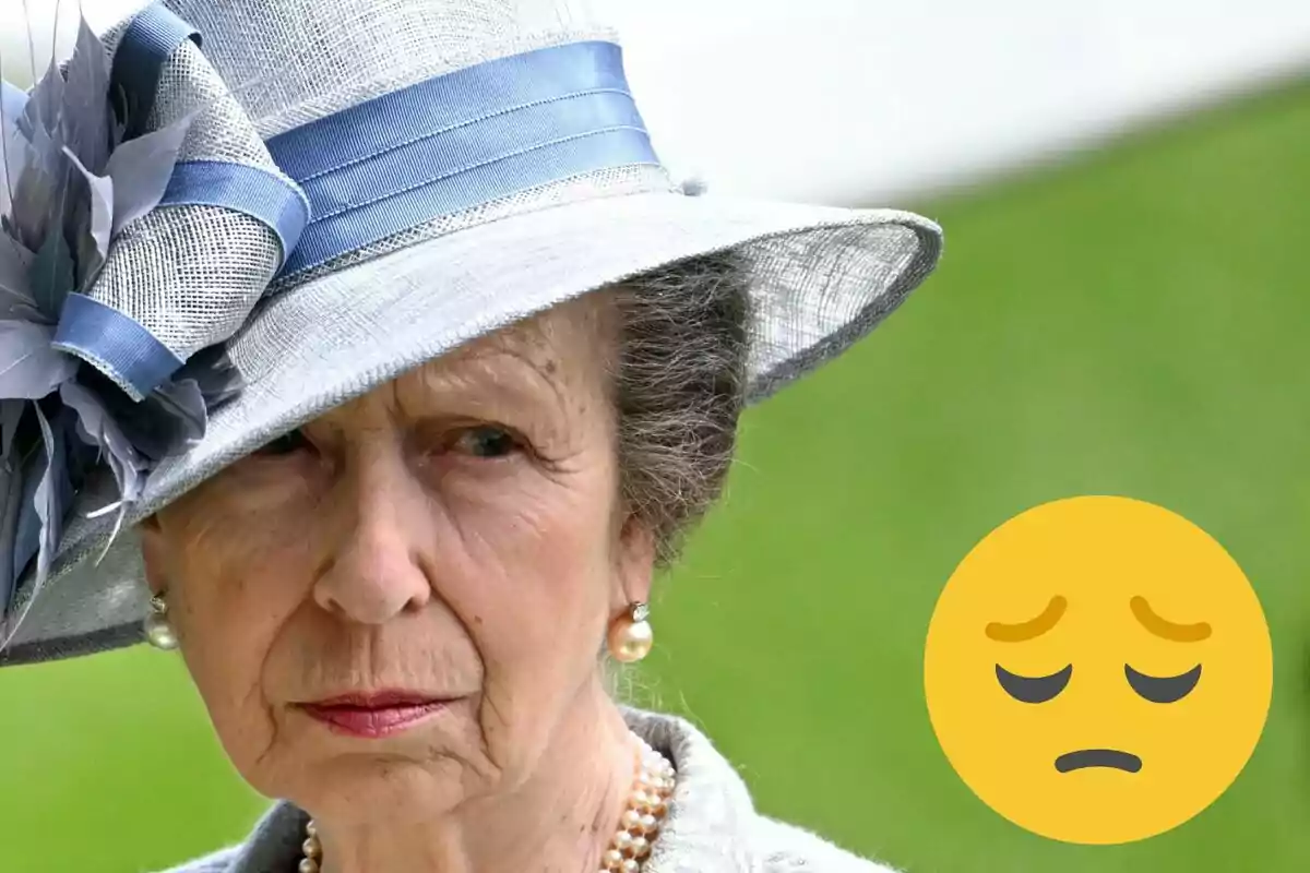 Ana de Reino Unido con sombrero elegante y expresión seria, acompañada de un emoji de cara triste.