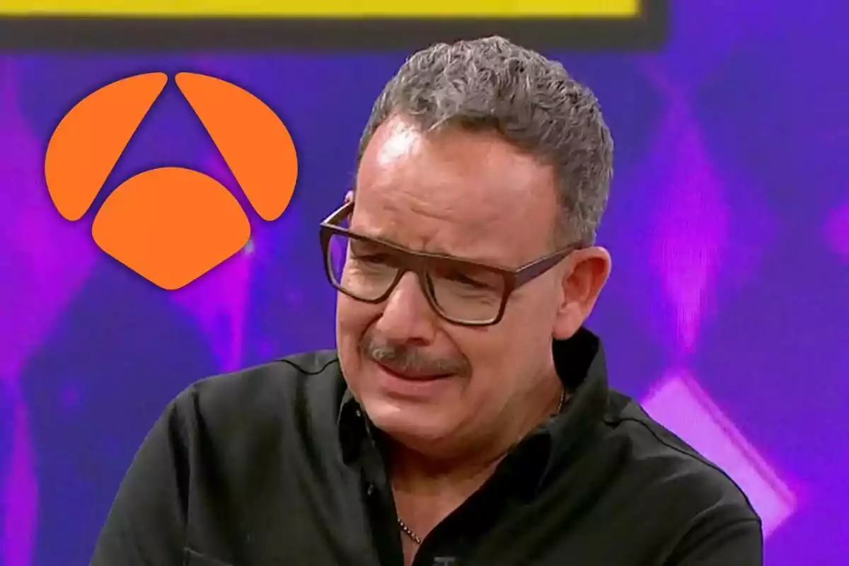 Àngel Llàcer con gafas y bigote, vestido de negro, aparece en un programa de televisión con un logotipo naranja en el fondo.