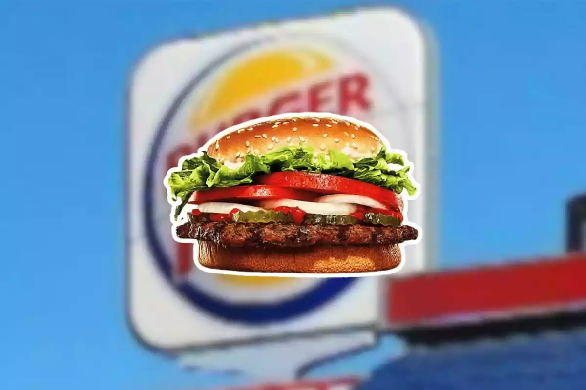 Burger with lettuce, tomato, and onion in front of a blurry fast food restaurant sign. Burger with lettuce, tomato, and onion in front of a blurry fast food restaurant sign.